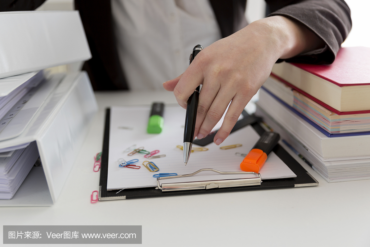 坐在滿(mǎn)是文書(shū),書(shū)籍和文件的桌子旁的女人。混亂的工作場(chǎng)所。過(guò)載和過(guò)度勞累